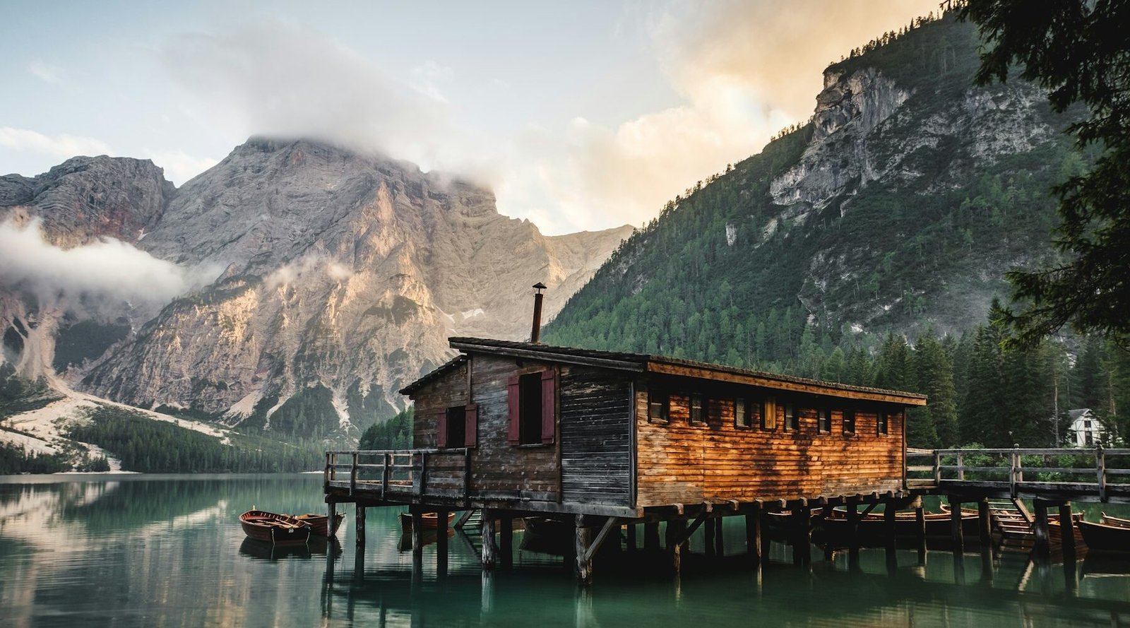 Wooden cabin on a mountain lake surrounded by peaks
