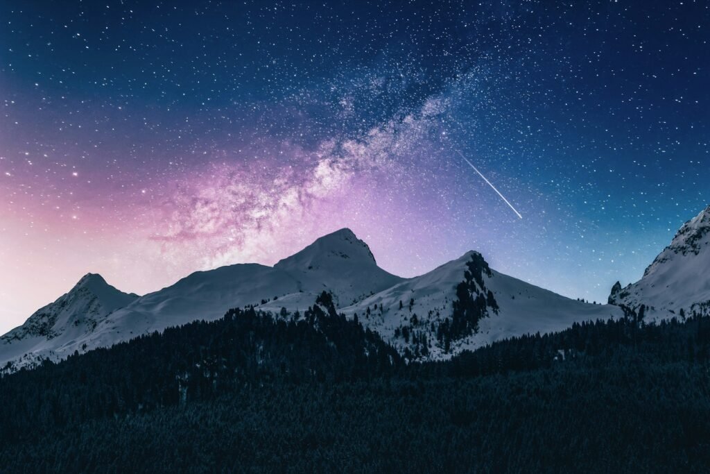 Snowy mountain peaks under a starry night sky