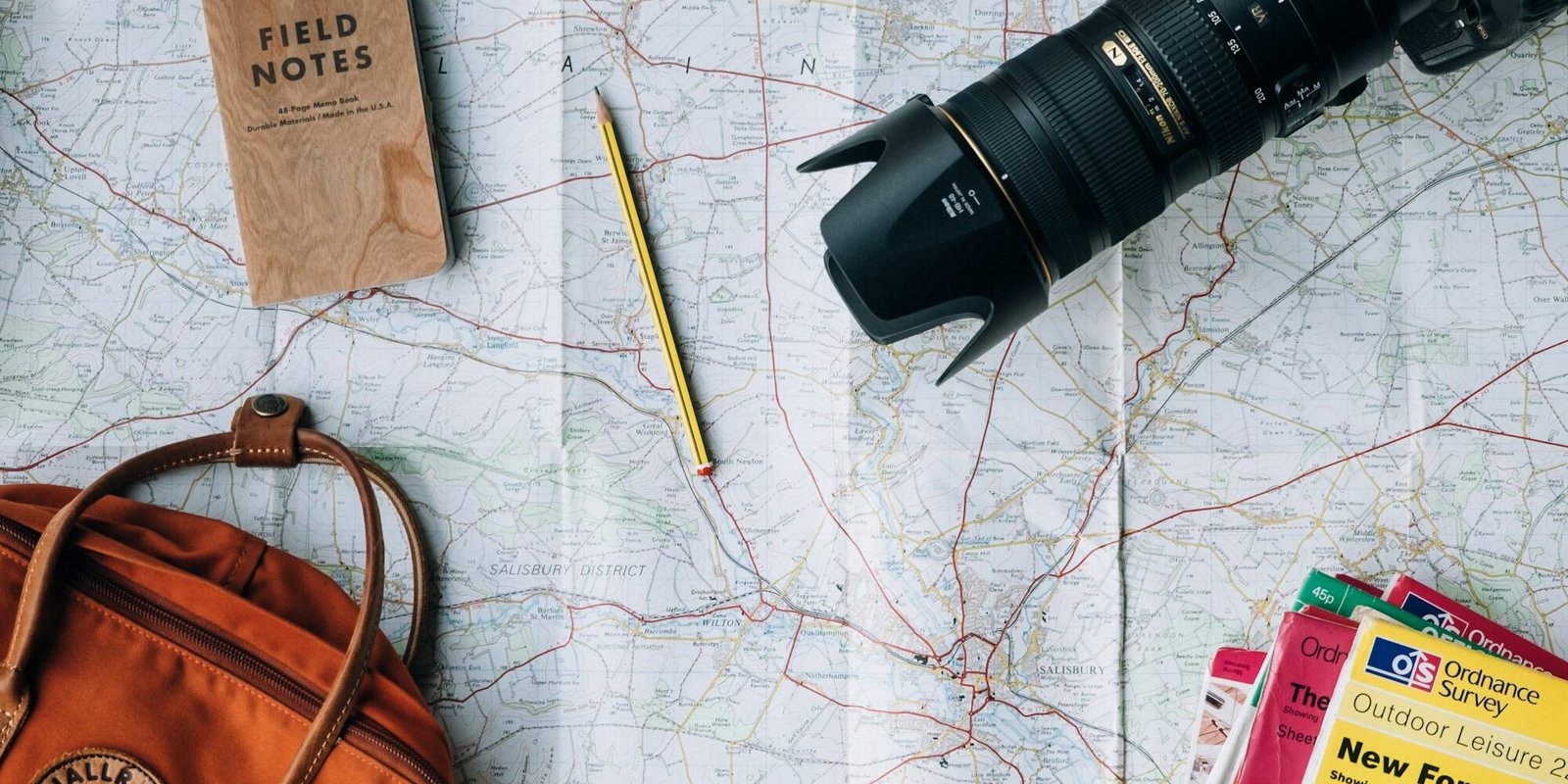 Travel planning flat lay with map, notebook, camera and passport essentials